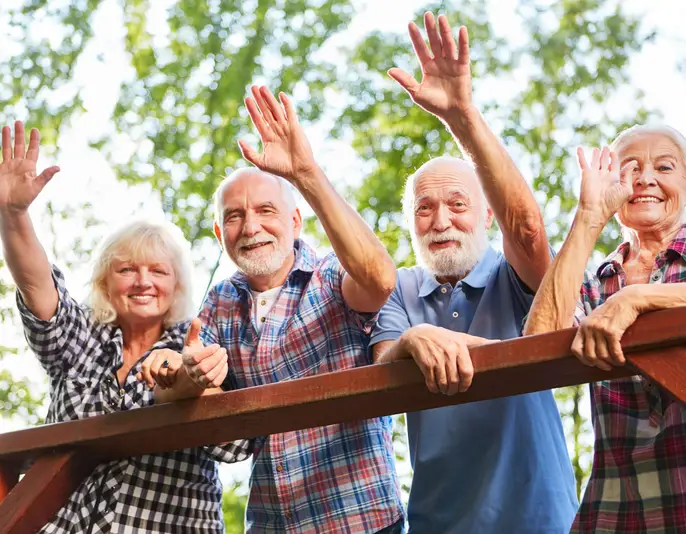 Cheerful seniors waving from a bridge on a summer outing